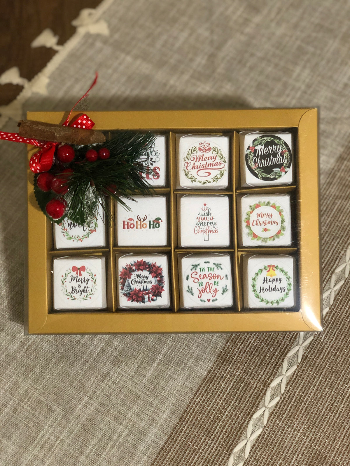 Set of Twelve Christmas-themed coasters in a decorative box on a textured surface
