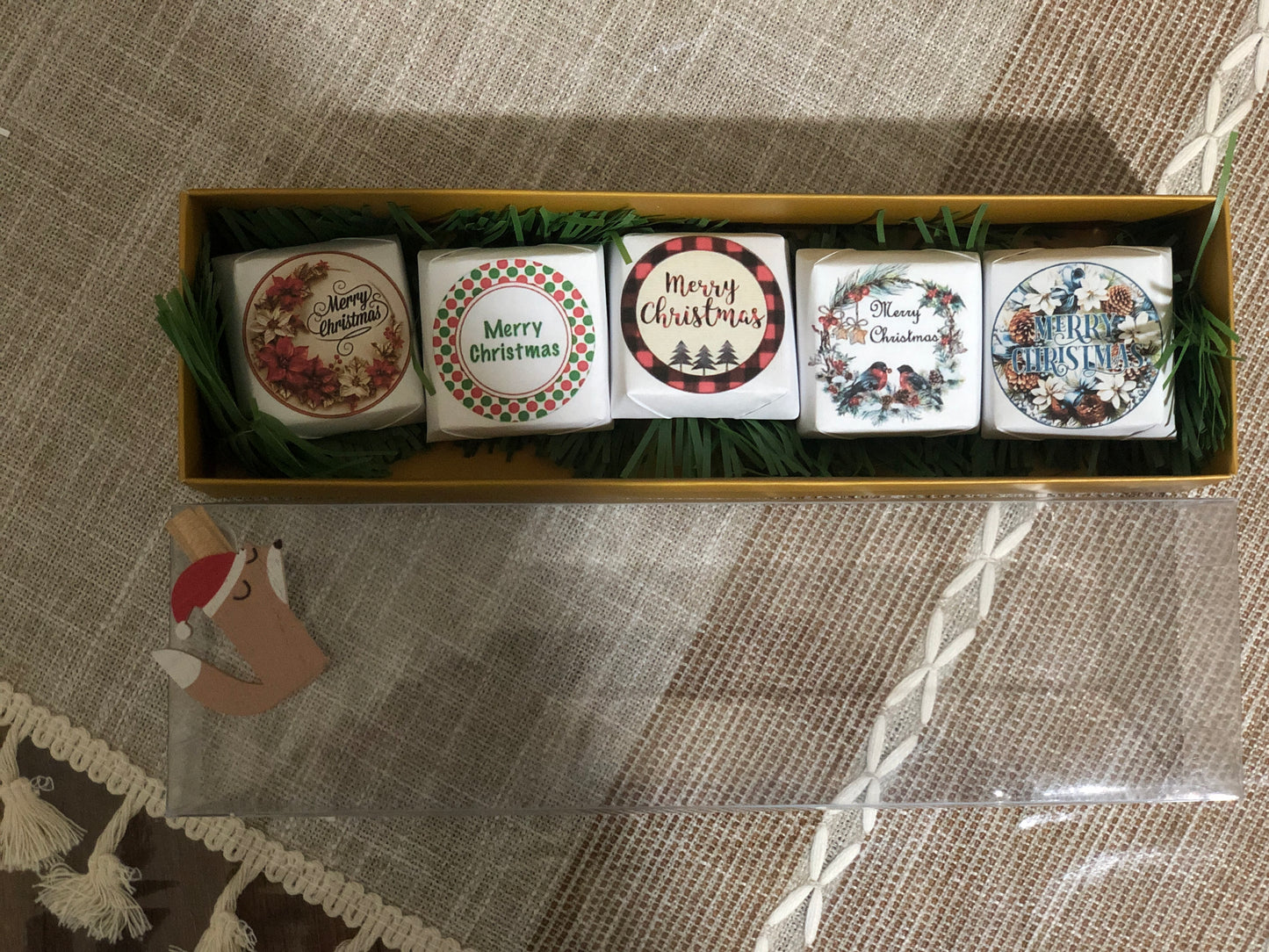 Set of five Christmas-themed coasters in a decorative box on a textured surface.