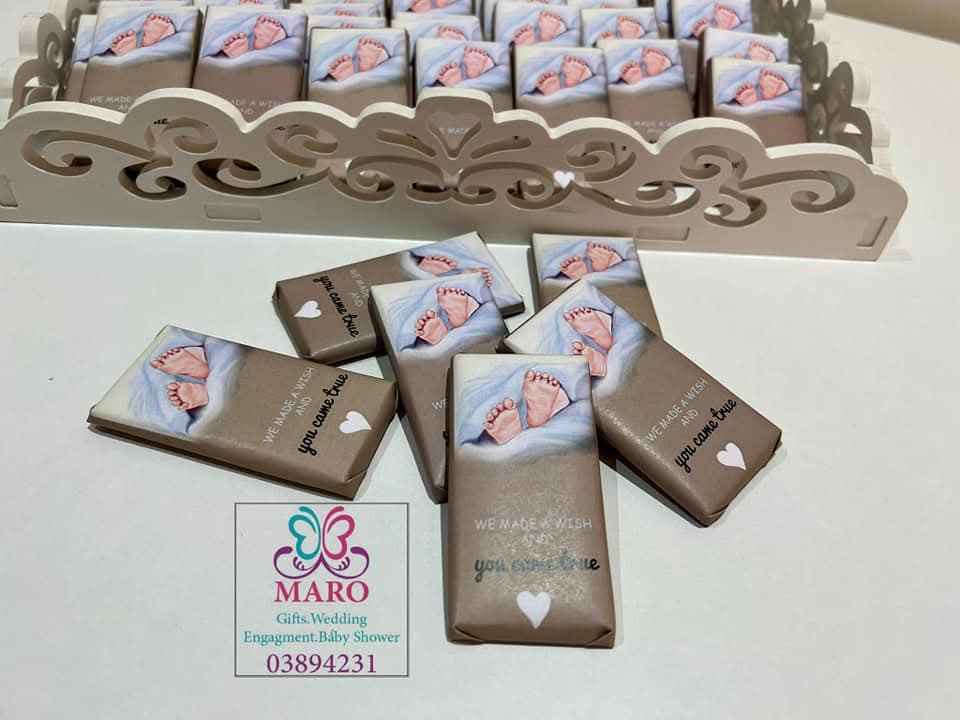 Chocolate bars with baby footprints and 'you came first' text, displayed on a decorative stand with MARO branding.