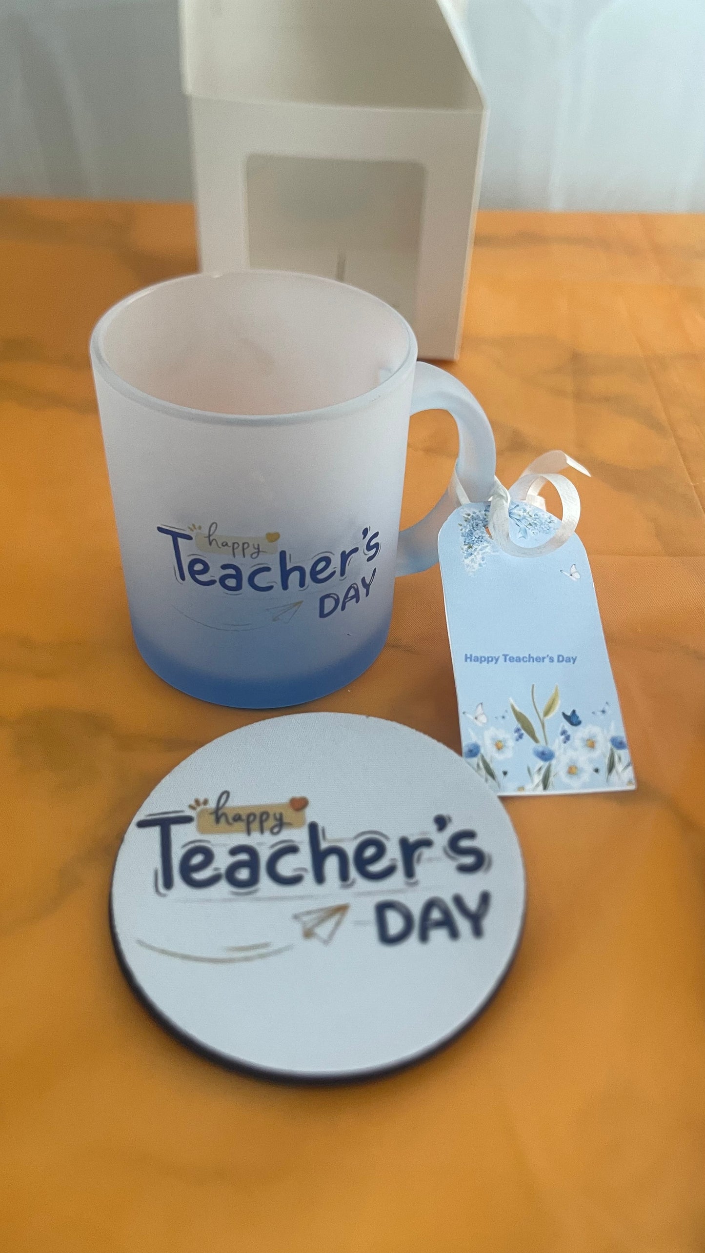 Blue Mug and coaster with 'Happy Teacher's Day' text on a wooden surface