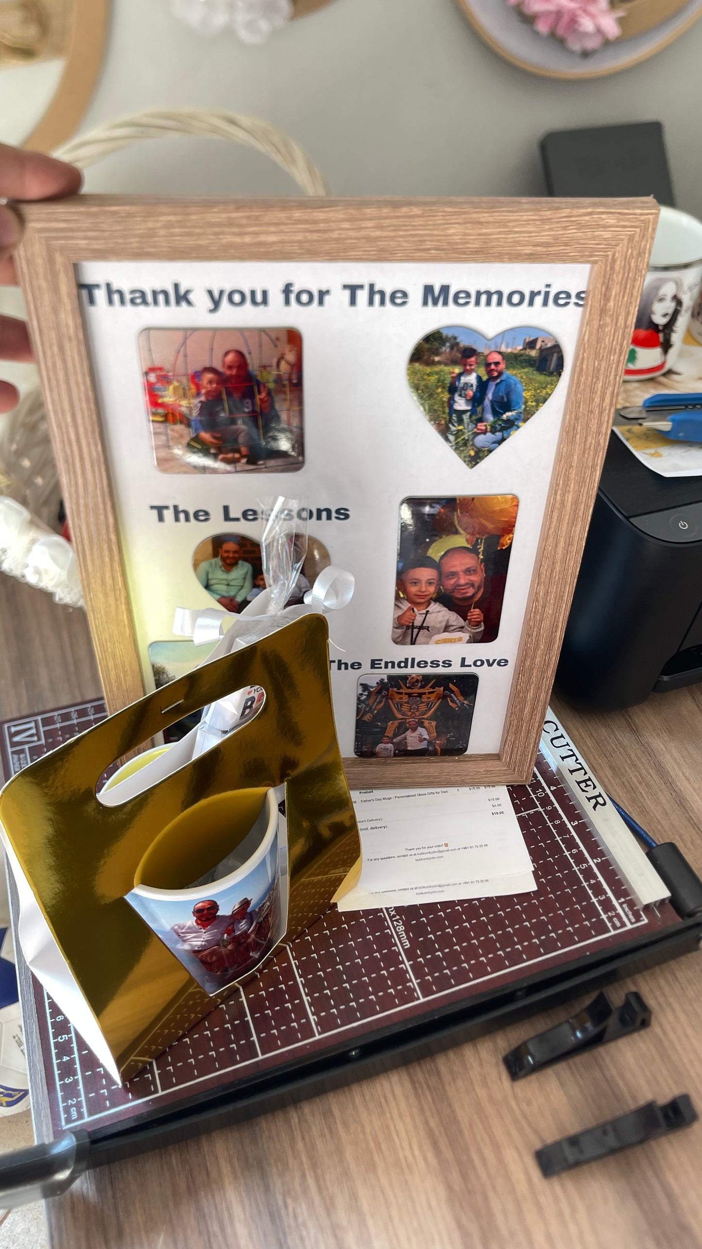 Memorial photo frame with cut-out photos and a mug on a table.
