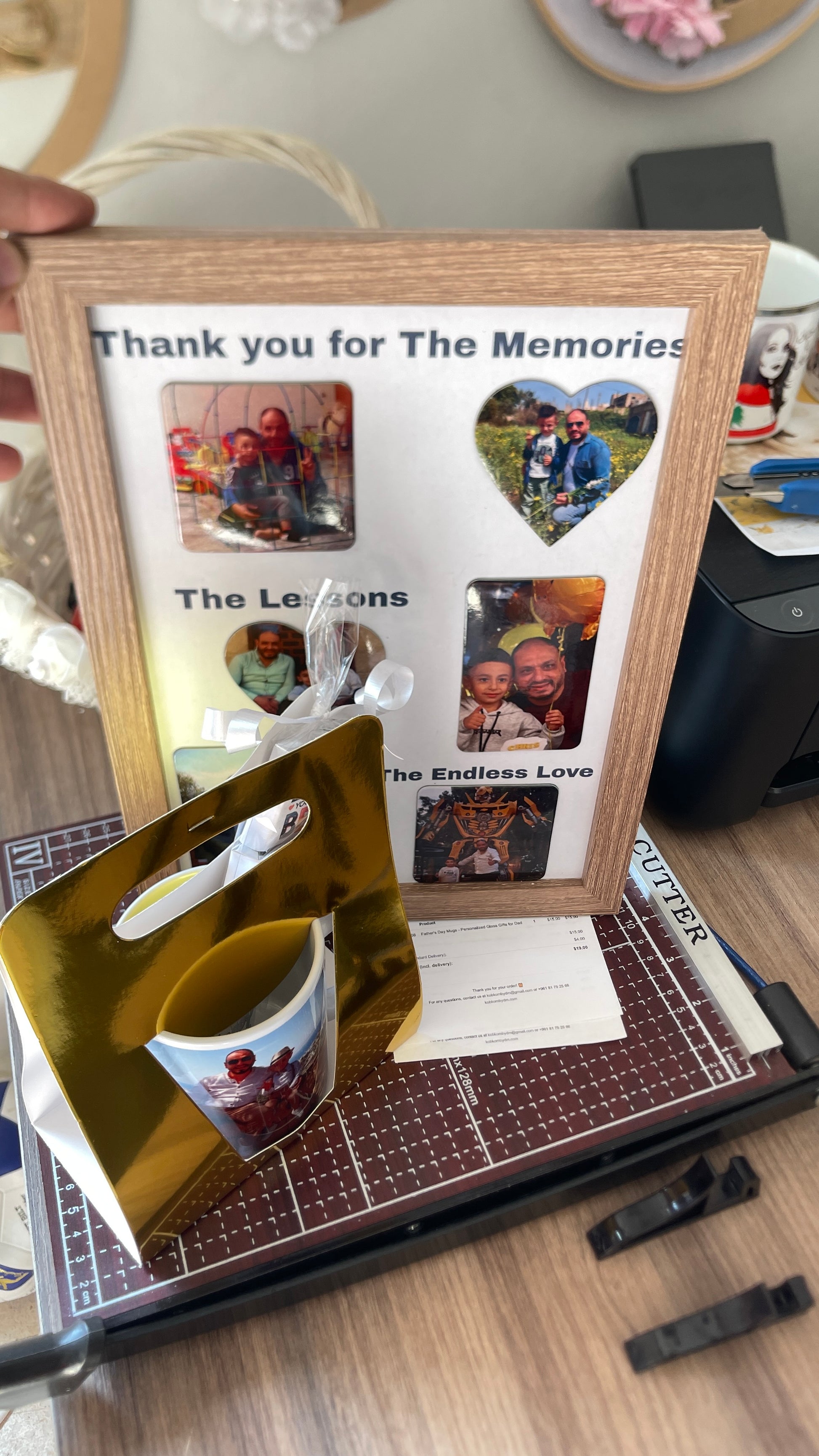 Memorial photo frame with cut-out photos and a mug on a table.