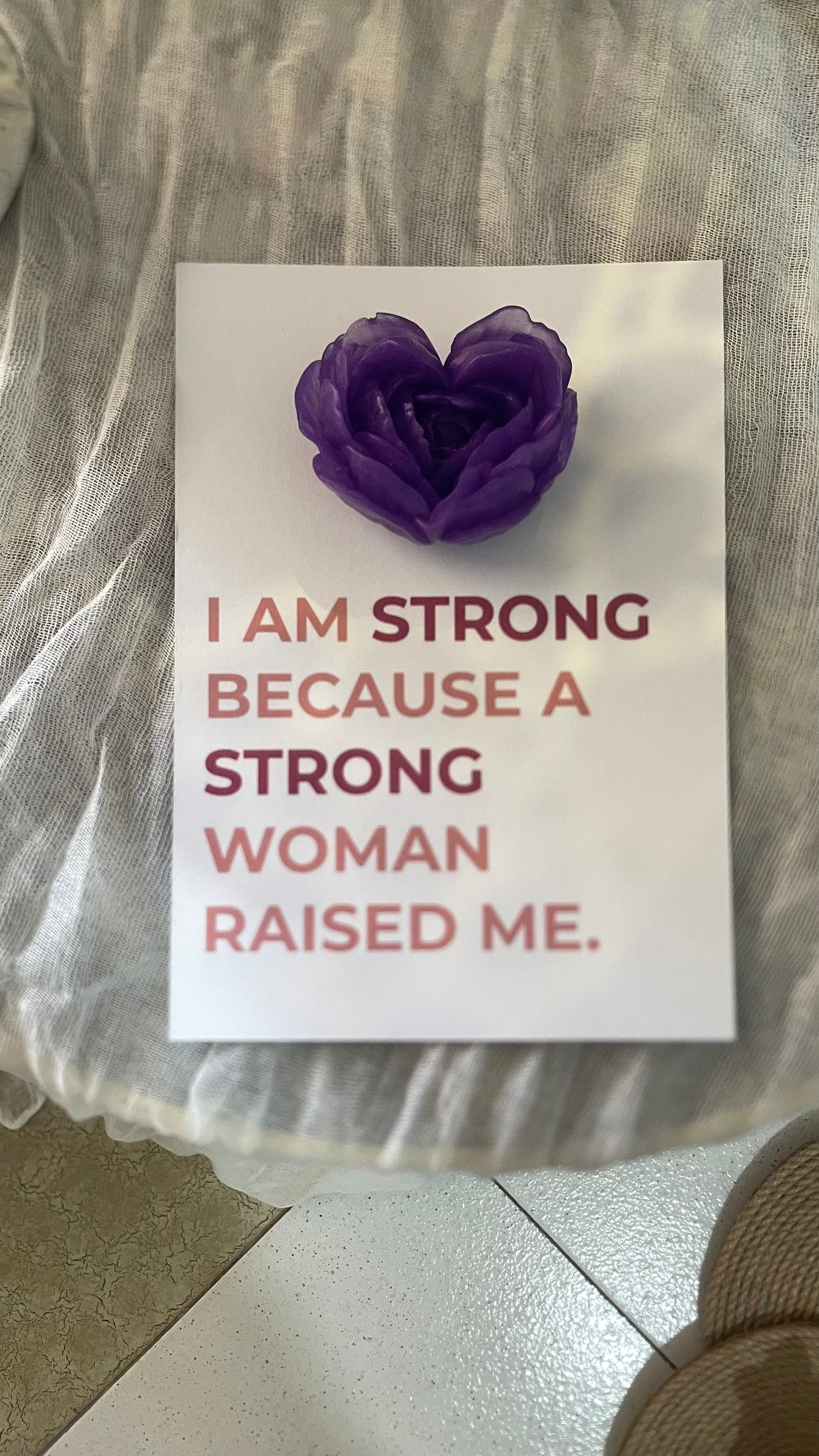 Card with purple flower and text on a textured surface