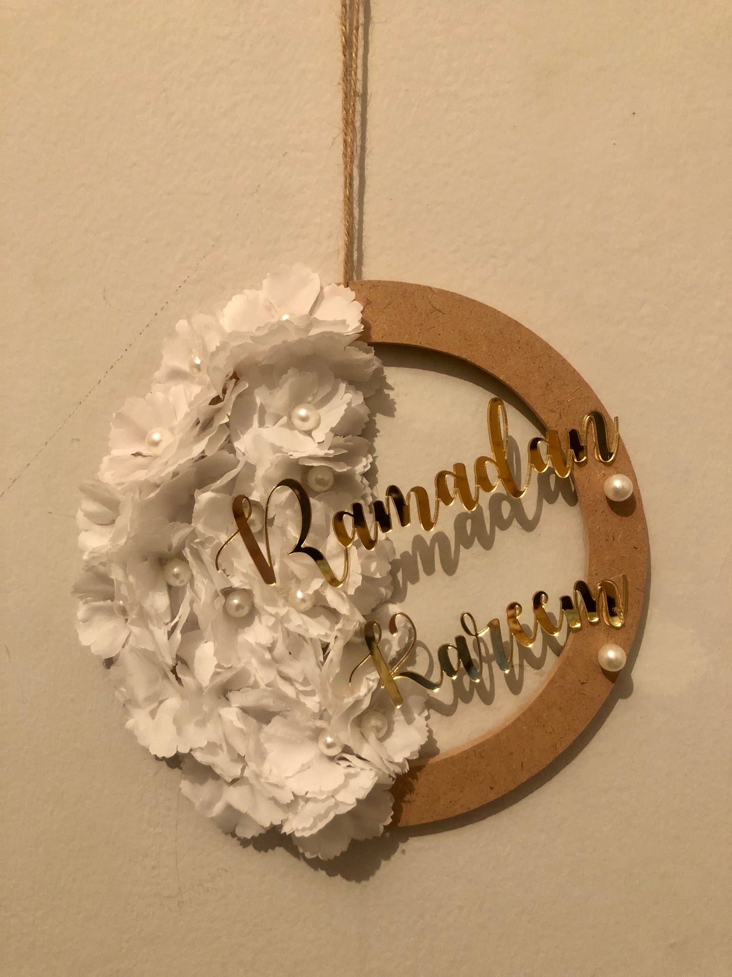 Decorative wall hanging with 'Ramadan Kareem' text and white floral design and wood