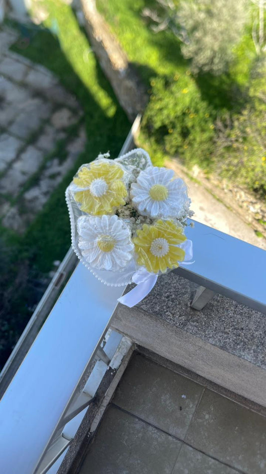 Decorative soap flower arrangement on a ledge with greenery in the background