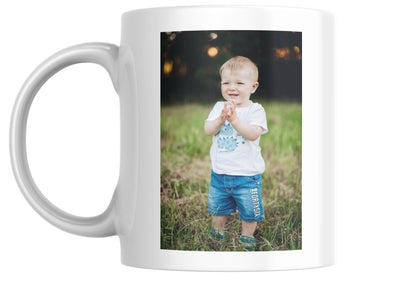 White mug with a photo of a child clapping on a grassy field