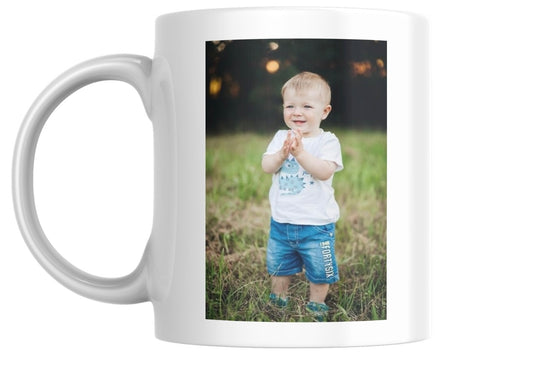 White mug with a photo of a child clapping on a grassy field
