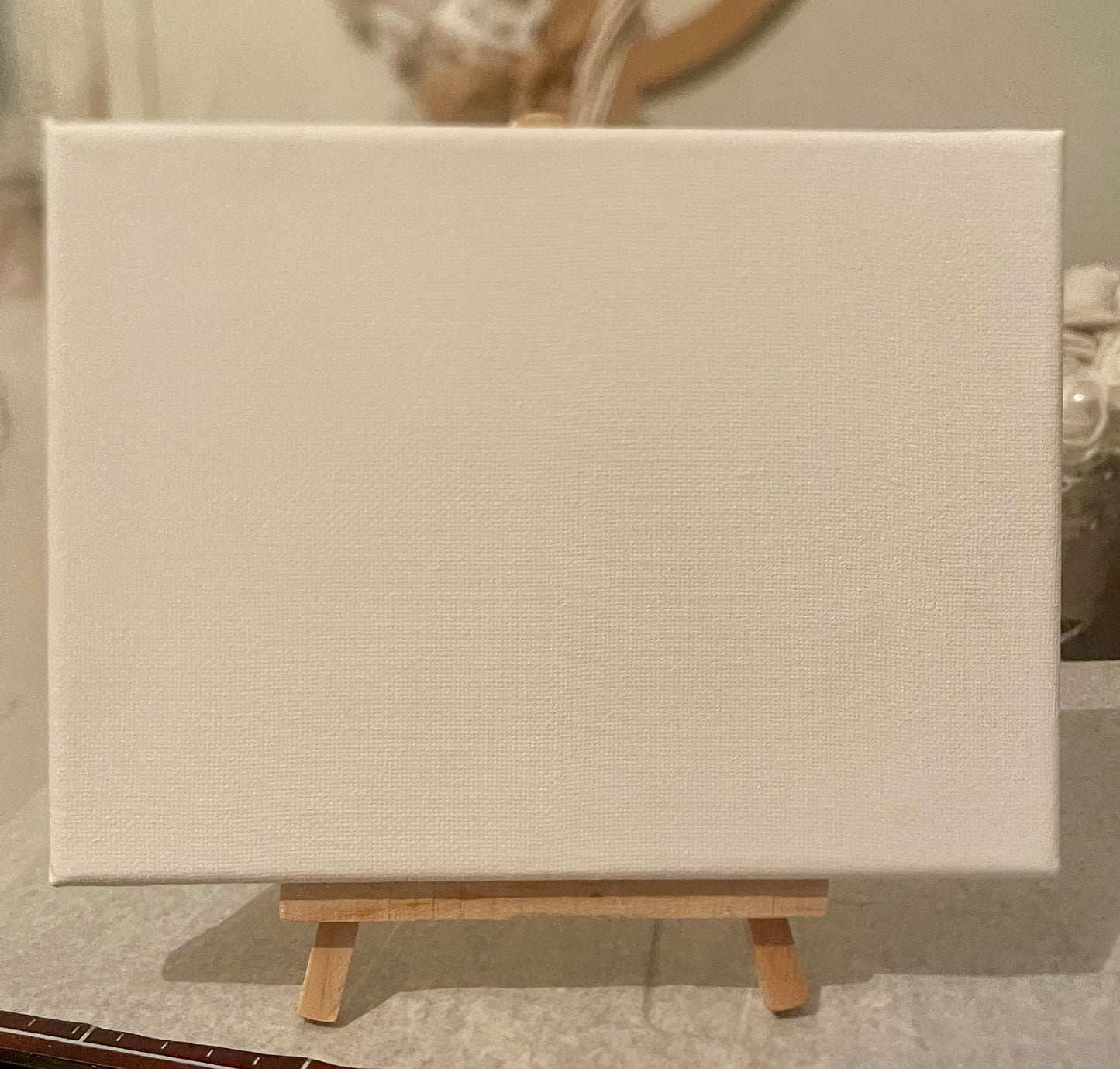 Blank canvas 20x20 with a small wooden easel against a neutral background