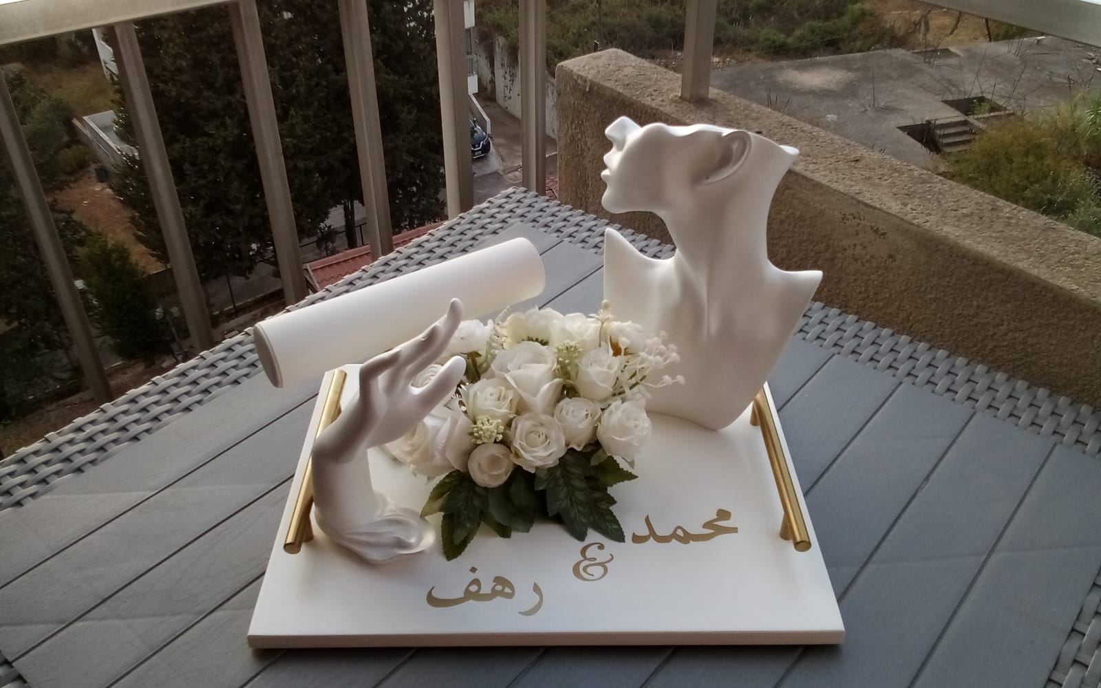 Personalized wedding keepsake tray with white couple sculpture, flowers, gold accents, and Arabic names