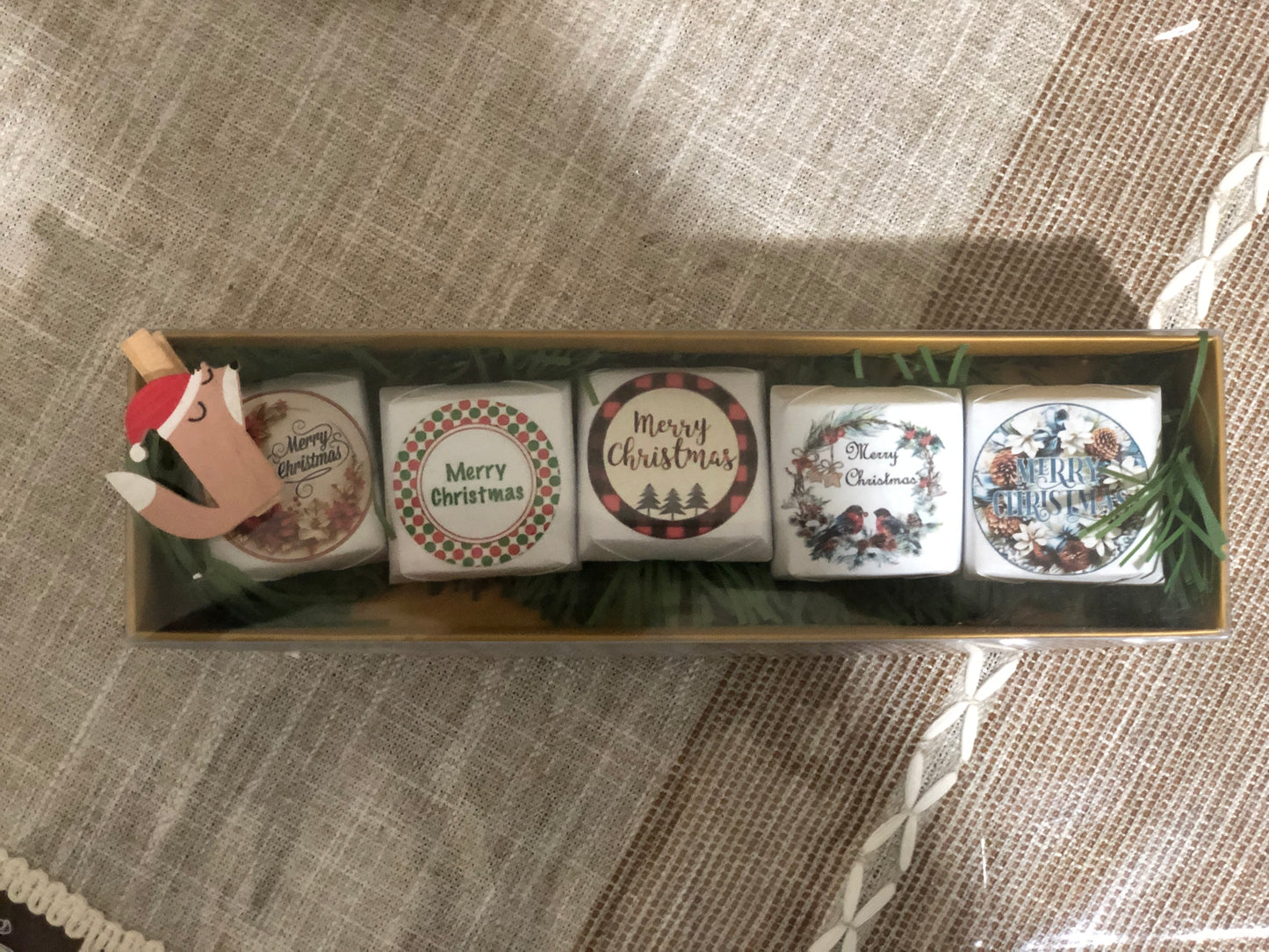 Set of Five Christmas-themed coasters in a decorative box on a textured surface