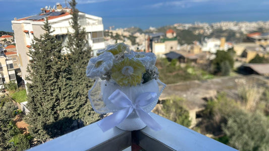 Decorative soap flower arrangement with a white bow on a balcony railing, overlooking a cityscape.